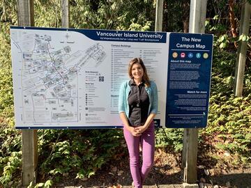Photo of VIU's new campus map with Dr. Victoria Fast standing in front of it.