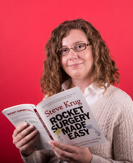 Lindsey holding a book called "Rocket Surgery Made Easy" and smiling