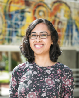 Image of a woman wearing glasses against a colourful background