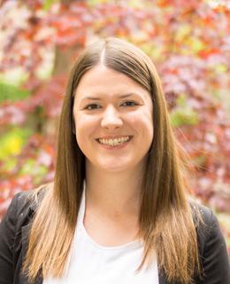  Headshot of Dr. Brittany Edgett from the shoulders up smiling in a white business casual top and black blazer.