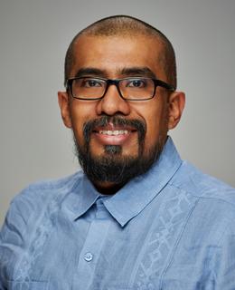 Smiling face with glasses and blue shirt.