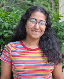 Tarini Fernando standing in front of a bush.