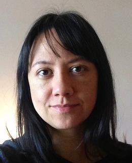 A picture of a woman with long dark brown hair and light skin looking straight at the camera.