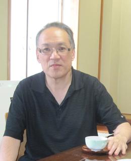 A man wearing glasses and a black t-shirt, having tea in Japan