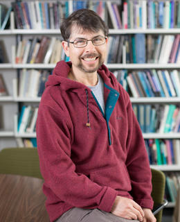 A smiling man in a burgundy sweater