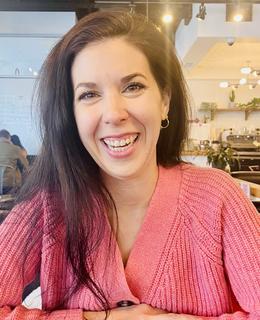 An image of Dr. Morgan Vanek seated and smiling. She has long brown hair, and wears a pink sweater.