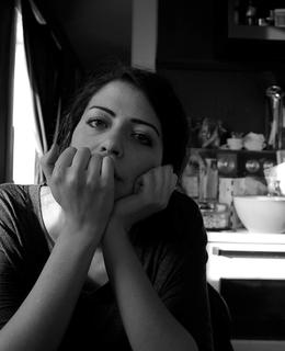 This is a black and white photo of Melody Dowdy sitting at a kitchen table with her head resting in her hands.