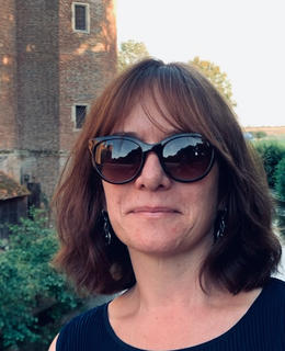 A photo of Dr. Jacqueline Jenkins outdoors. She has short brown hair and wears sunglasses.