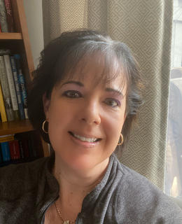 Head and shoulders profile photo in front of a bookcase and curtains.