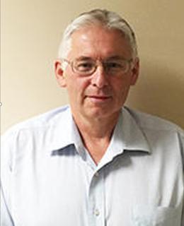 Headshot of Chris Holdsworth wearing a white collared shirt in front of a beige background.