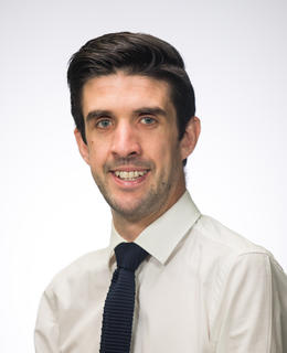 Headshot. White shirt, navy blue tie.