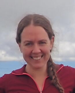 A photo of Cecilia standing on top of a mountain. 