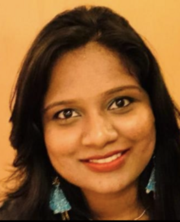 Picture of a thirty year old woman, cropped at neck, with turquoise earrings and red lipstick. 