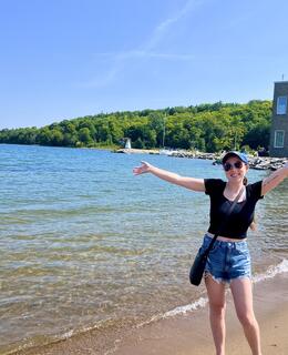 Larissa standing in front of a lake with her arms stretched out 