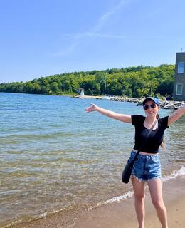 Larissa standing in front of a lake with her arms stretched out