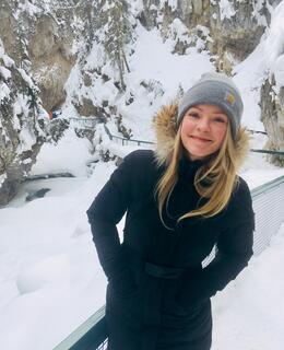 Woman in a toque and winter coat outdoors on a snowy trail