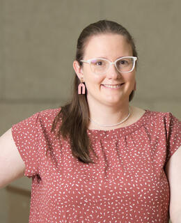 A picture of Robyn in burnt orange shirt standing and smiling at the camera.