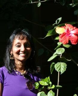 Dr. Malhi standing next to hibiscus flowering plant
