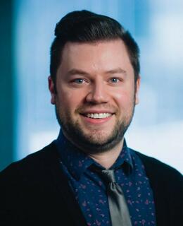 Image of white man with brown hair wearing a shirt and tie.