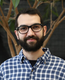 Photo of Rodrigo Dal Ben standing in front of a tree.