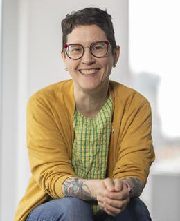 A woman with short brown hair and glasses smiles at the camera. 