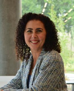 Dina smiling while sitting and looking over her left shoulder