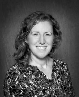 Black and white photo of a smiling woman with curly shoulder length hair