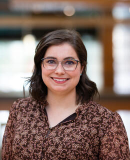 A young woman with glasses in a brown dress in the Taylor Institute