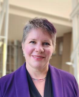 person with short hair and a purple blazer