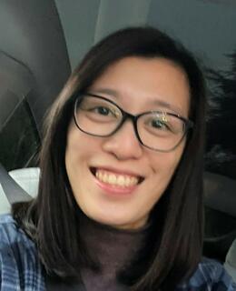 Image of Kelly with medium length black hair and black cat eye glasses smiling