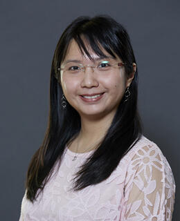 female headshot with dark long hair and a pink shirt and wearing a glasses