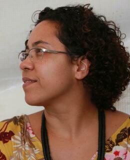 Karla looking to other side and using a yellow shirt and long neckless