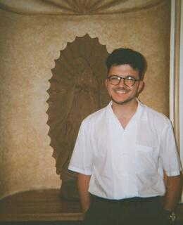 Person in white shirt and glasses in front of painting