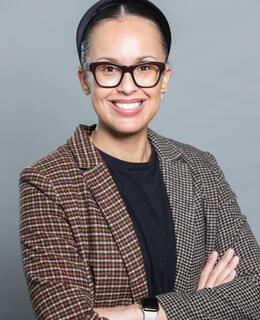 Image of 33 year old woman, tan complexion, wearing glasses and a patterned blazer.