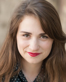 A headshot of Megan, brunette with brown eyes.