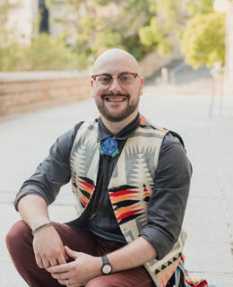 Geordie Cowan in an Indigenous vest and beaded bolo tie at the University of Saskatchewan campus.
