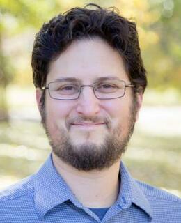 Smiling, bearded man in blue collared shirt