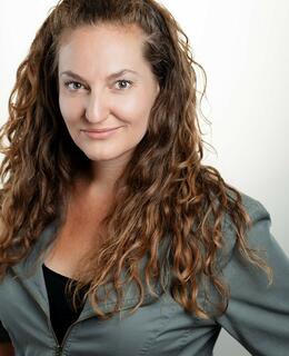 Jacqueline Russell in a blazer in front of a white wall.