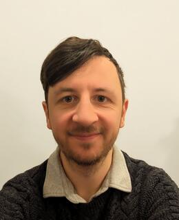 Headshot of Edwin Dickinson smiling against grey backdrop.