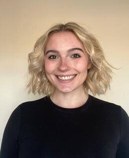 Aimee is wearing a black long-sleeve shirt against a white background.