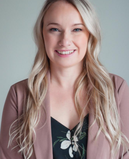 Profile picture of a woman in a pink blazer with long blonde hair, smiling 