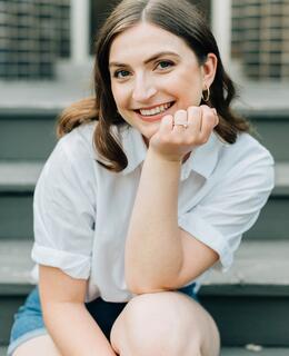 Elizabeth smiling, seated on stairs.