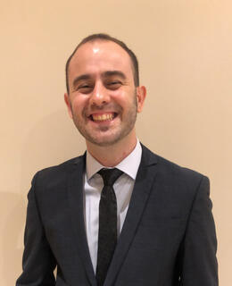 He is wearing a black tuxedo and smiling