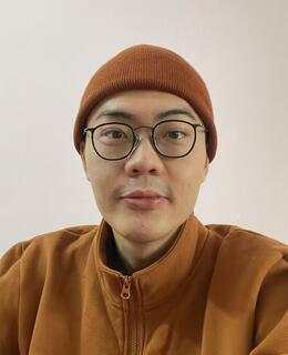 An Asian person wearing a camel-colored hoodie and knit beanie